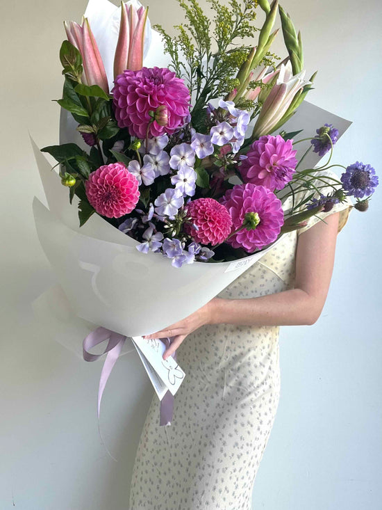 Bouquet of flowers held by a person with a plain background