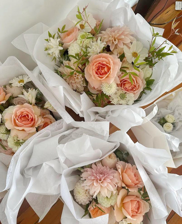 Bouquets of flowers wrapped in white paper on a wooden surface
