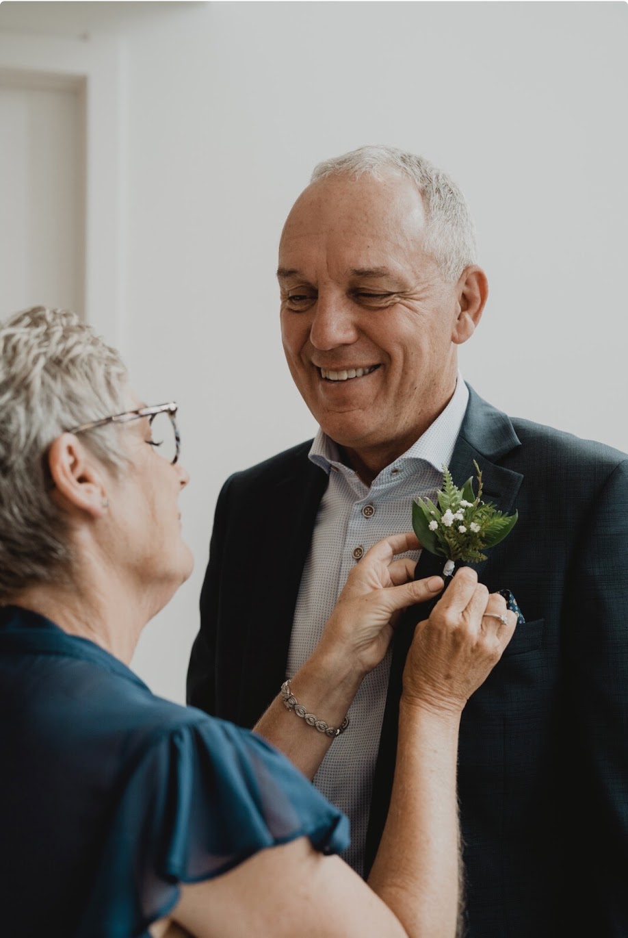 Woman adjusting a boutonniere on a man's suit jacket