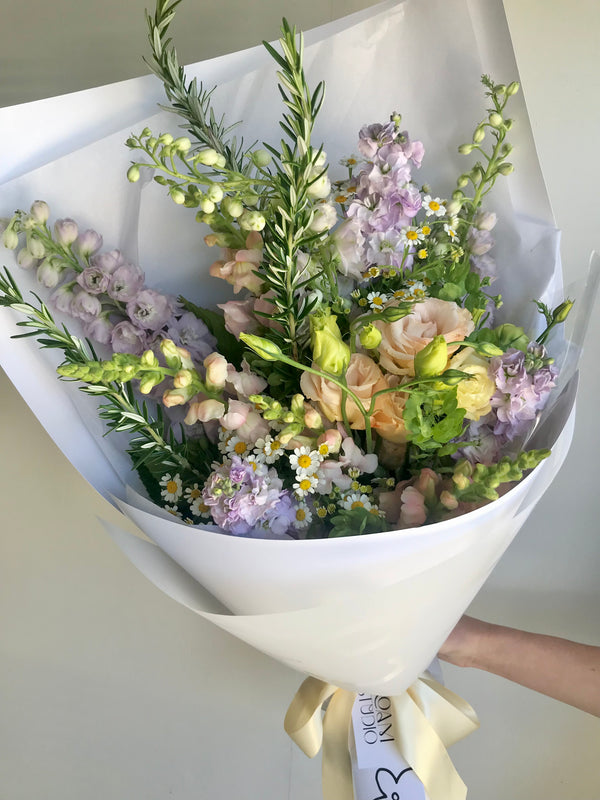 Flower bouquet in pastels with peach, purple and daisy