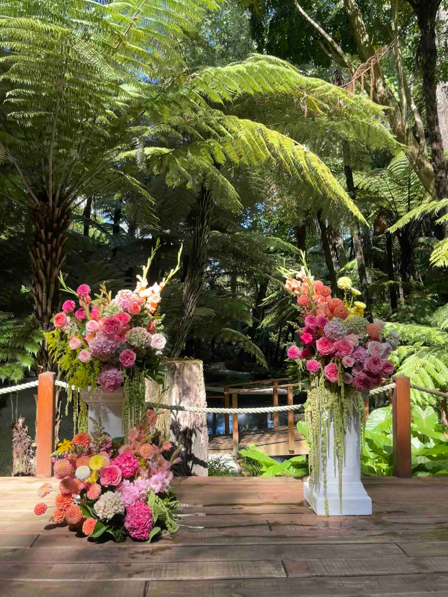 Floral arrangements on white plinths in a forest setting