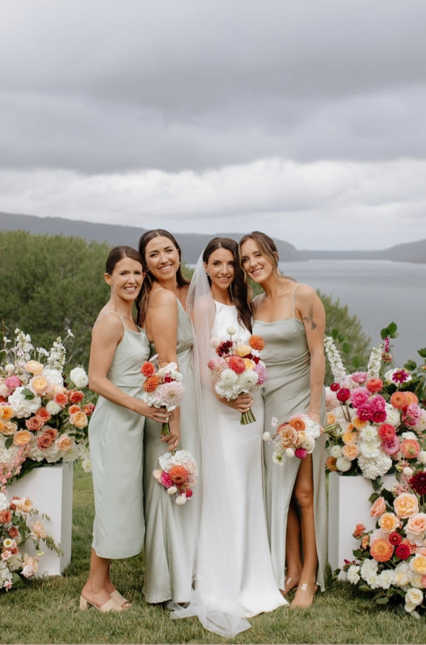Bride and bridesmaids posing outdoors with floral decorations and a scenic background
