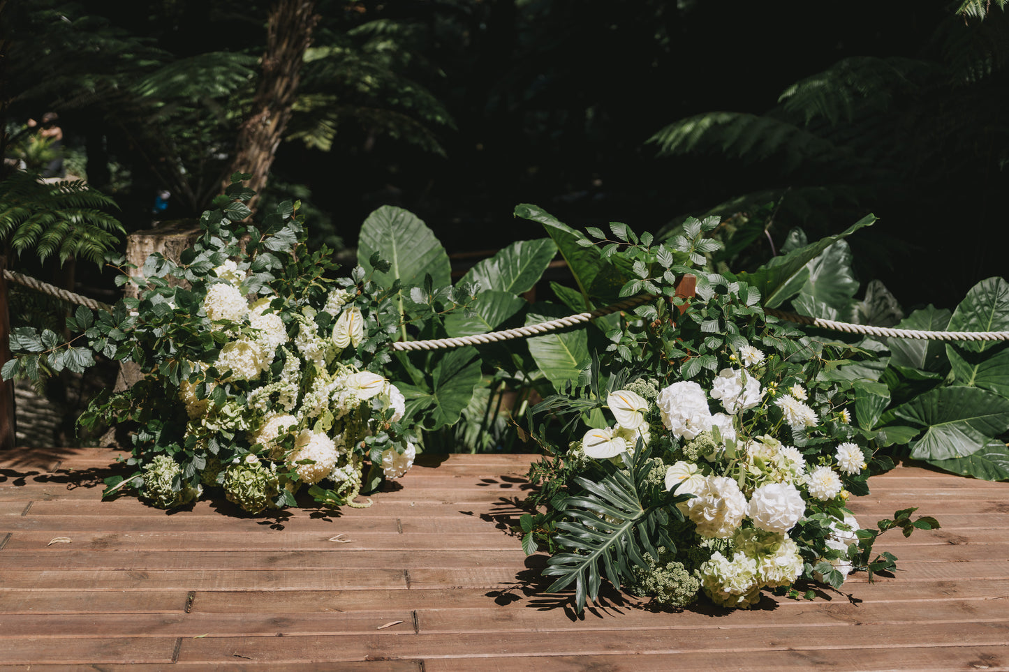Decorative floral arrangement on a wooden platform with green foliage in the background
