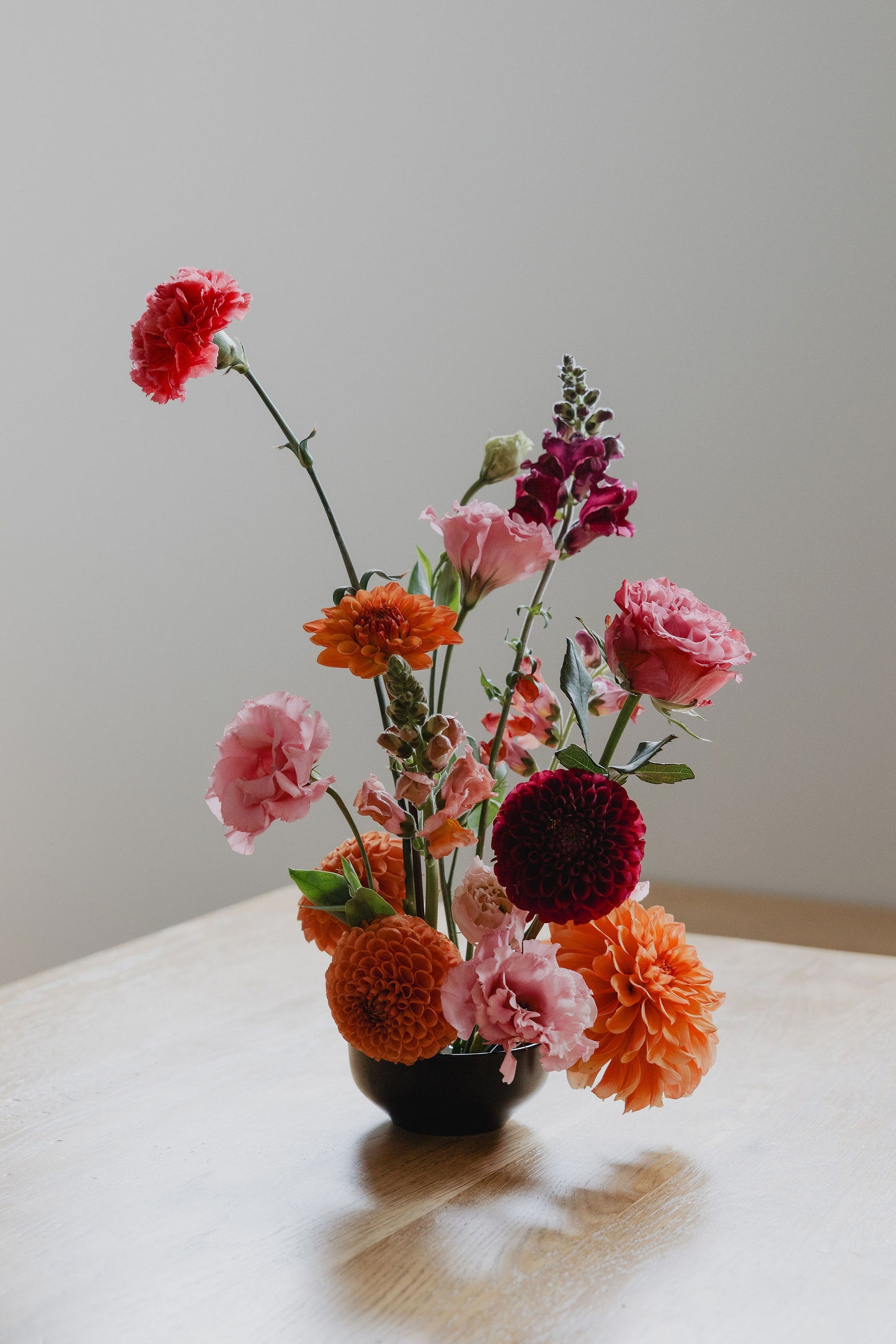 Bouquet of colourful flowers in a vase on a light surface with a neutral background