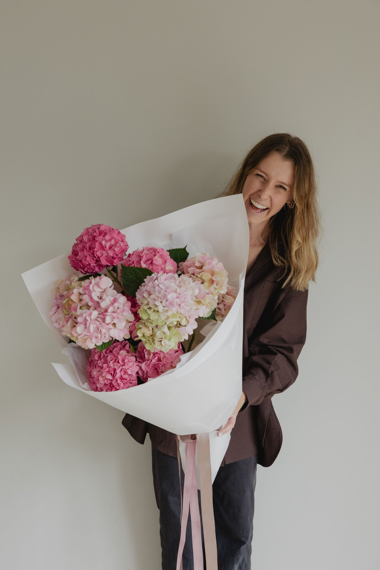 Woman holding a large pink hydrangea bouquet wrapped in white paper for Mother’s Day by Roam Studio Florist