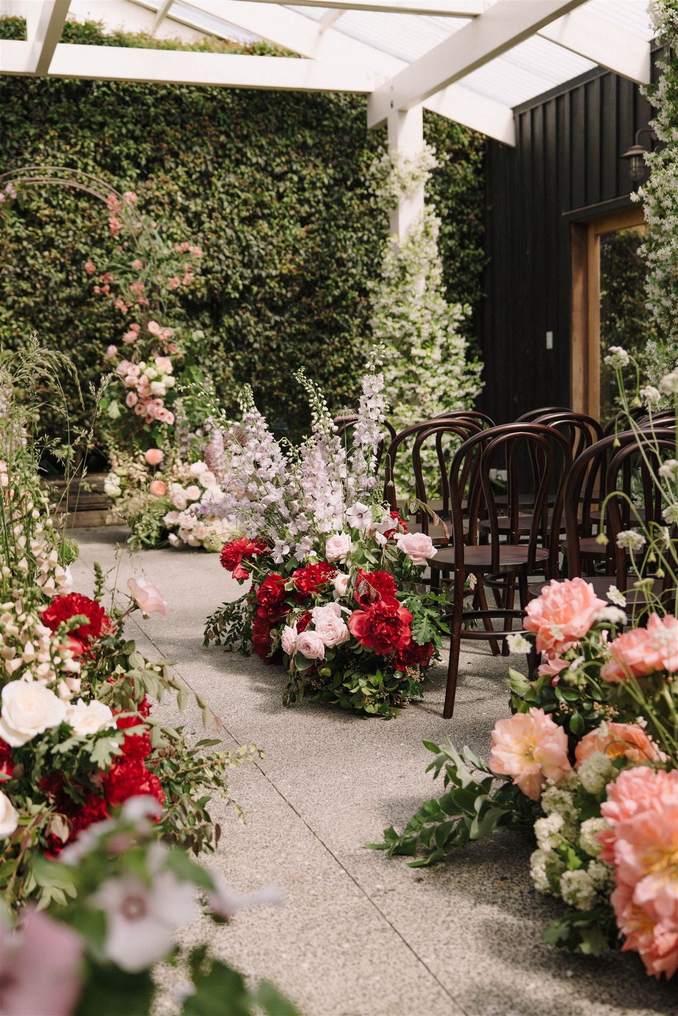 Decorative floral arrangements along a aisle with chairs in an outdoor setting.