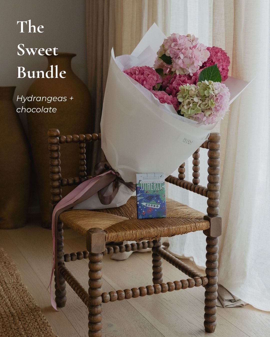 Bouquet of hydrangeas on a wooden chair with a box of chocolates underneath, labeled 'The Sweet Bundle'.