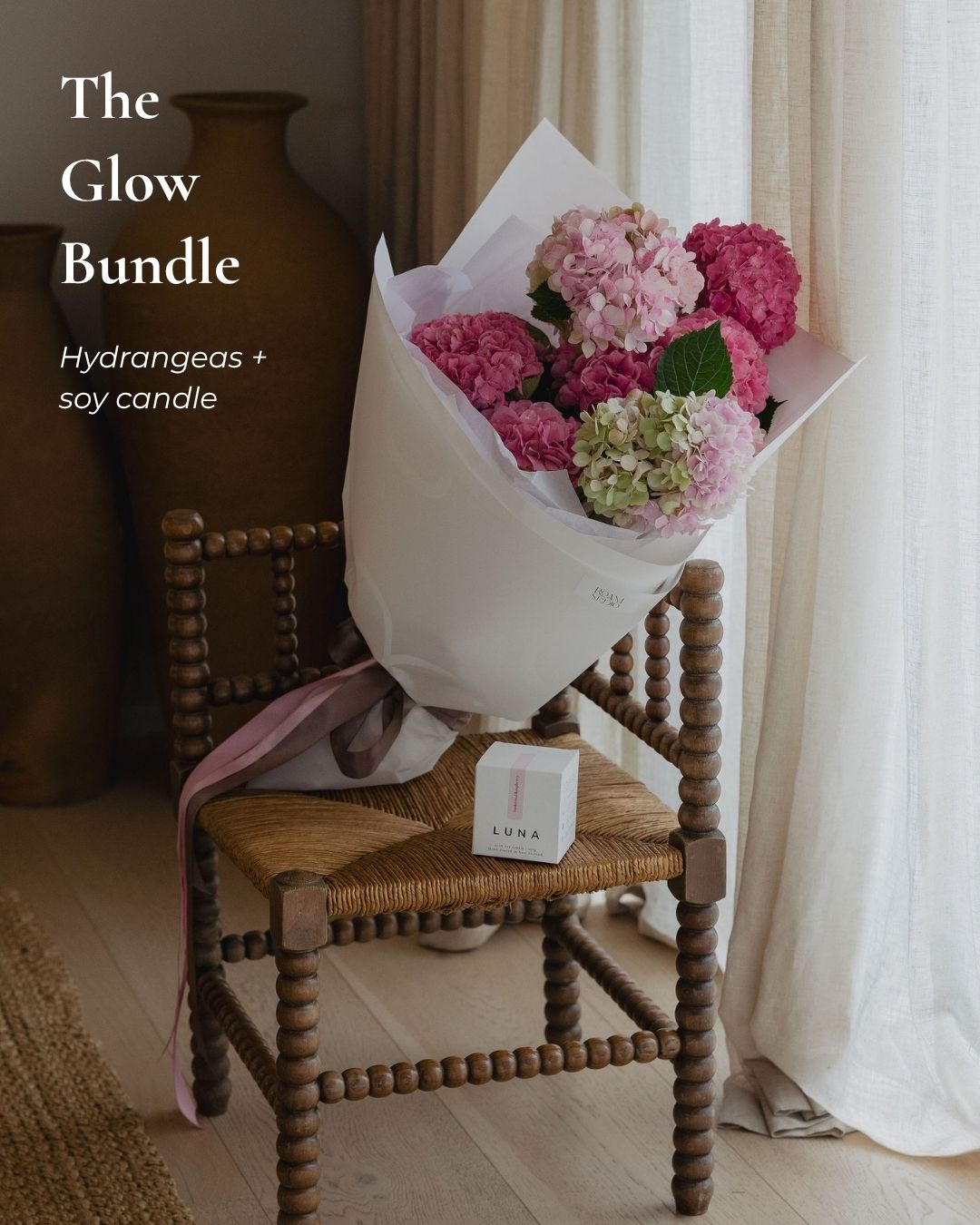 Bouquet of pink hydrangeas on a wooden chair with a soy candle labeled 'The Glow Bundle'.