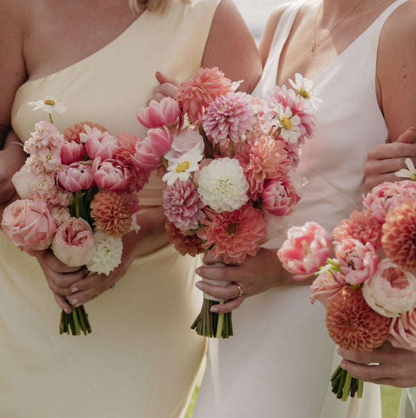 Three women holding pink and white flower bouquets.