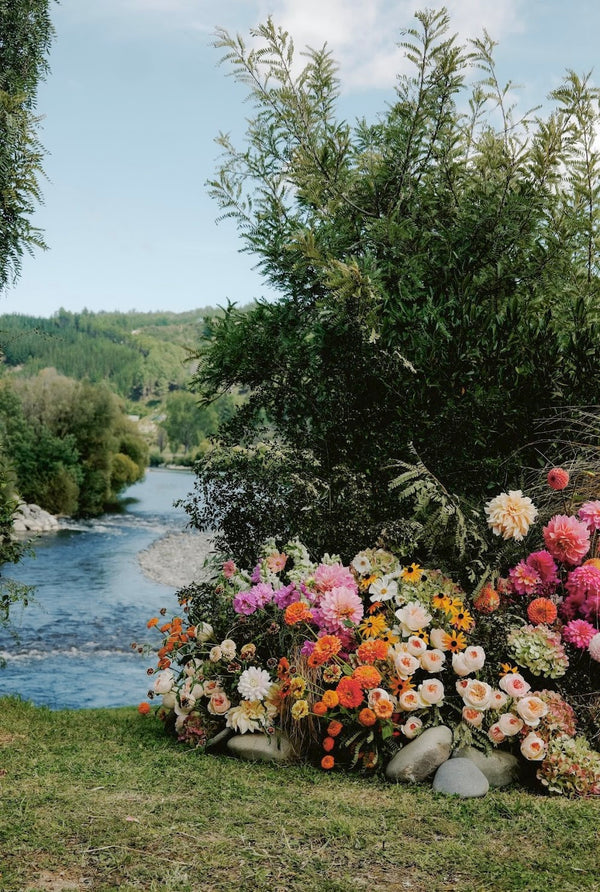 Floral arrangement by a river with greenery and trees in the background